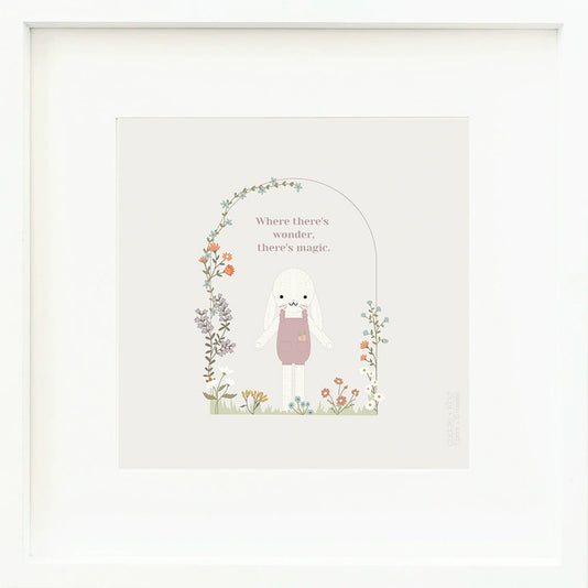 An inspirational print with a graphic of Harper the bunny surrounded by a flower covered archway on a purple background with the words “Where there’s wonder, there’s magic” in lilac.