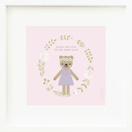 An inspirational print with a graphic of Olivia the honey bear inside a ring of floral vines on a soft purple background with the words “Bloom into who you are meant to be” in darker purple.