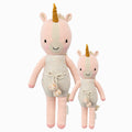 Ella the unicorn in the regular and little sizes, shown from the front. Ella is wearing a white romper with confetti polka dots and a pom-pom waist tie.
