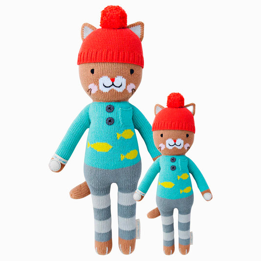 Maximus the cat in the regular and little sizes, shown from the front. Maximus is wearing a blue sweater with yellow fish on it, gray striped pants, and a red pom-pom hat.