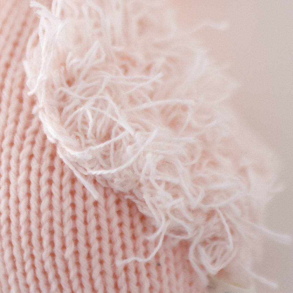 A close up showing the hand-knit details on baby flamingo, including its fluffy yarn wing.