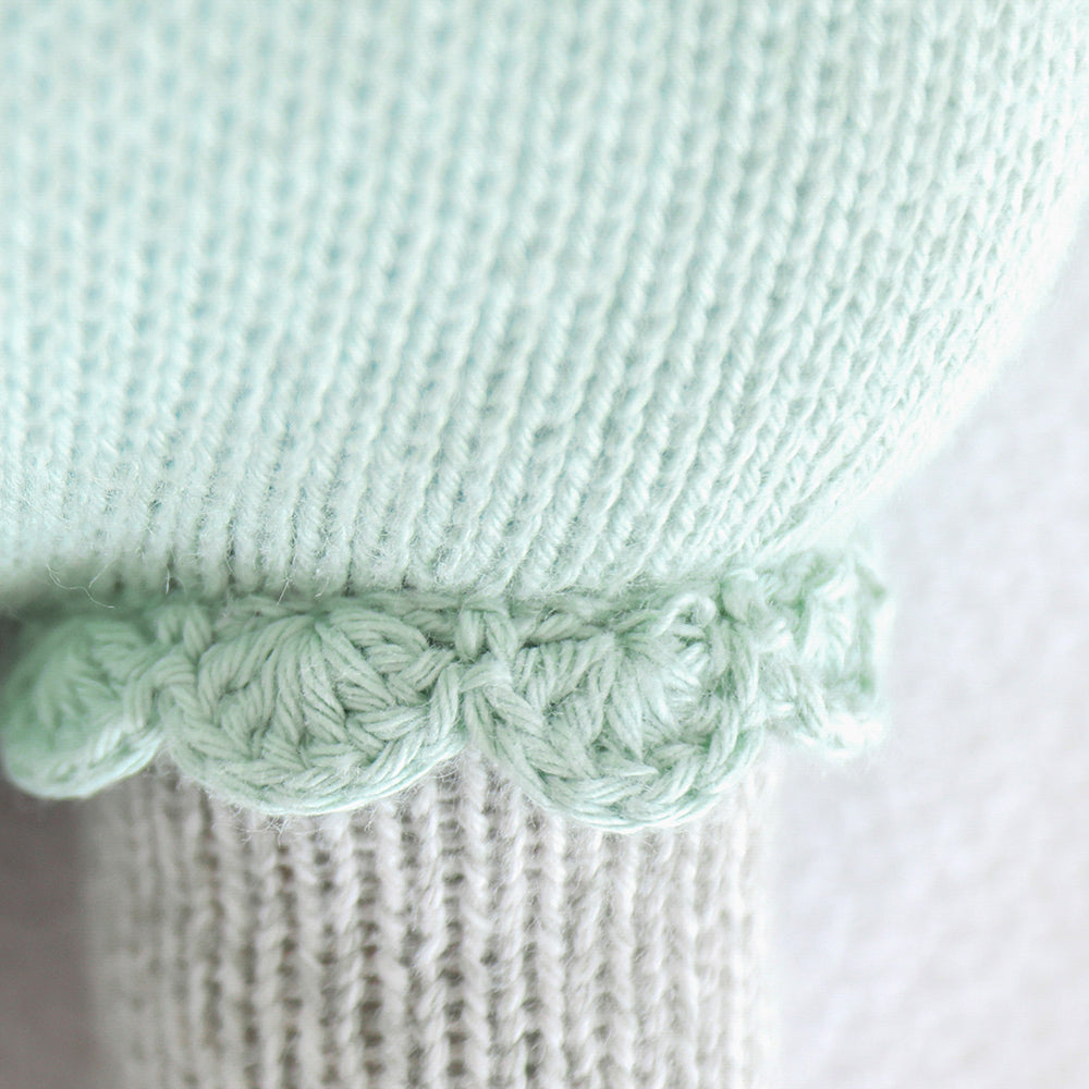 A close-up showing hand-knit details on the leg of Claire the koala’s romper.