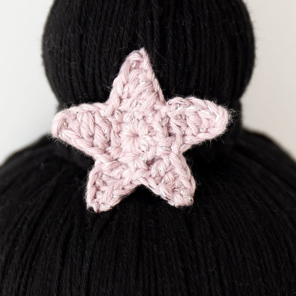A close-up showing the hand-knitted star on top of Luna’s bun.