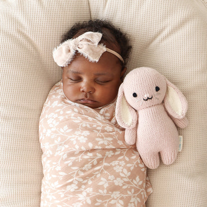 A sleeping baby snuggled next to a baby in rose.