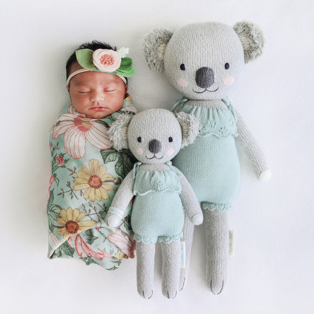 A sleeping baby with two Claire the koala dolls in the little and regular sizes.