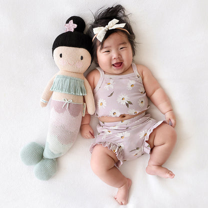 A laughing baby with a Luna the mermaid doll.
