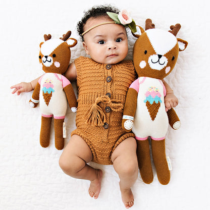 A baby with her arms around Willow the deer dolls in the little and regular sizes.