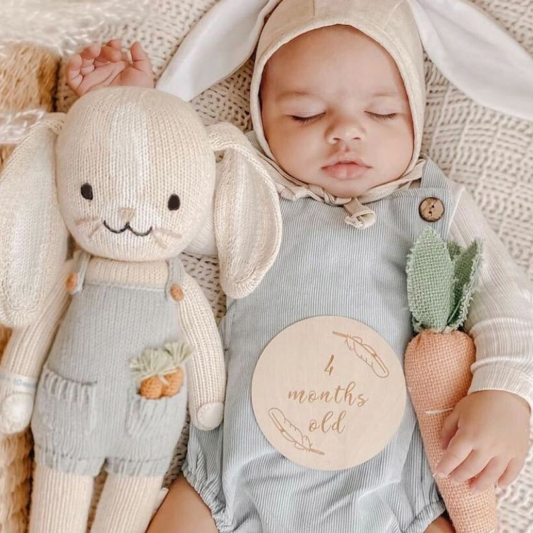 A sleeping baby wearing a bunny-eared bonnet snuggled beside Henry the bunny.