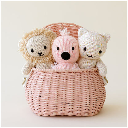 Three baby animal stuffed dolls peeking out of a pink basket: baby lion, baby flamingo and baby kitten.