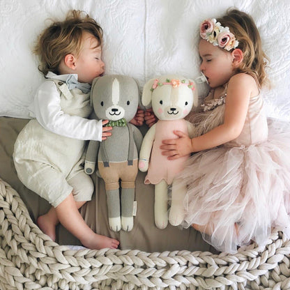 Two sleeping babies lying side-by-side with two knit stuffed animals, Noah the dog and Charlotte the dog.