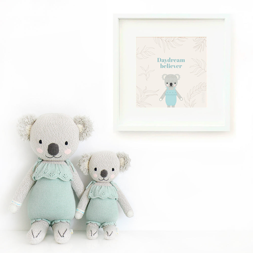 Two Claire the koala stuffed dolls sitting beside a framed print with a picture of Claire that says “Daydream believer.”