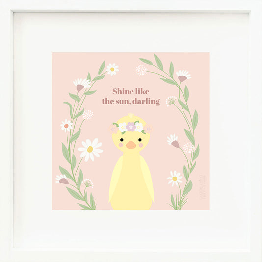 An inspirational print with a graphic of Flora the duckling on a pink background with leafy, floral vines rising from bottom to top and words that say “Shine like the sun, darling” in mauve.