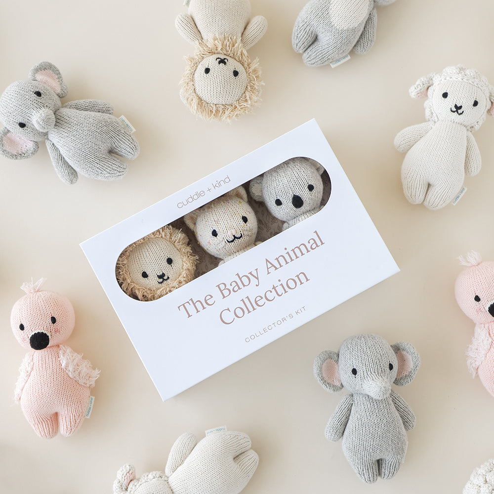 Three baby animals peeking out of a baby animal collector’s kit box, surrounded by eight other baby animal dolls.