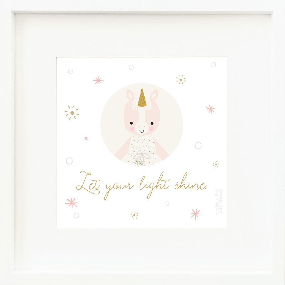 A framed print with a drawing of Ella the unicorn and text that says “Let your light shine.”