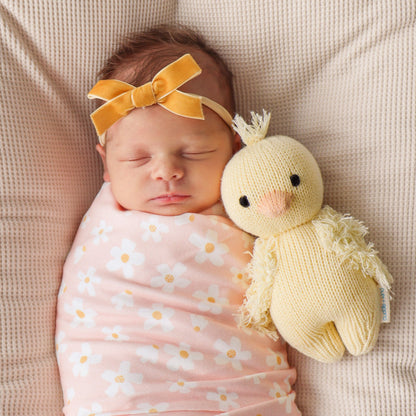 A sleeping baby snuggled next to baby duckling.