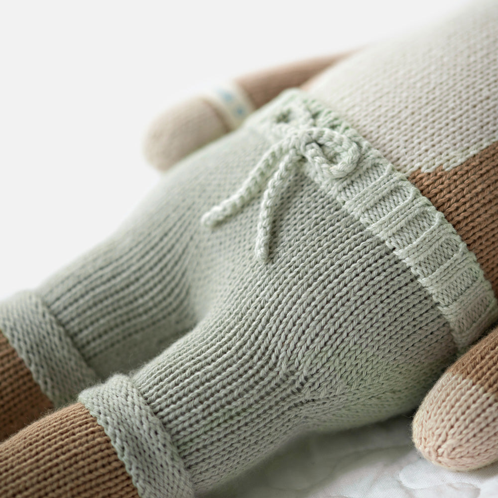 A close-up showing hand-knit details on Elliott the fawn, including the hand-knit tie on his shorts.