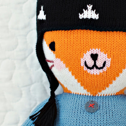 A close-up showing hand-knit details on Sadie the fox’s face and her knitted hat.