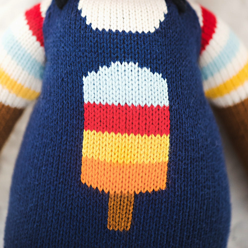 A close-up showing hand-knit details on Scout the deer, including a popsicle design on his overalls.