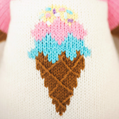 A close-up showing hand-knit details on Willow the deer, including an ice cream cone design on her romper.