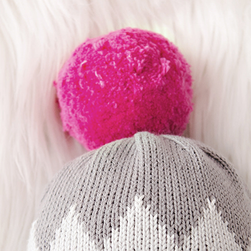 A close-up of the pink pom-pom on Aspen the penguin doll's hat.