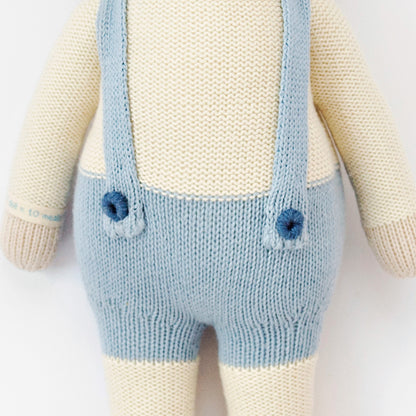 A close-up showing hand-knit details on Sebastian the lamb, including the embroidered yarn buttons on his suspenders.