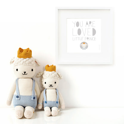 Two Sebastian the lamb stuffed dolls sitting beside a framed print with a picture of Sebastian that says “You are loved little prince.”