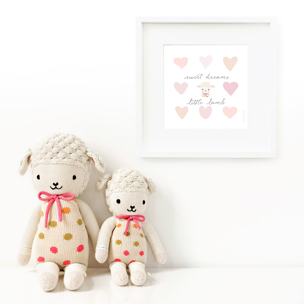 Two Lucy the lamb stuffed dolls sitting beside a framed print with a picture of Lucy that says “Sweet dreams, little lamb.”
