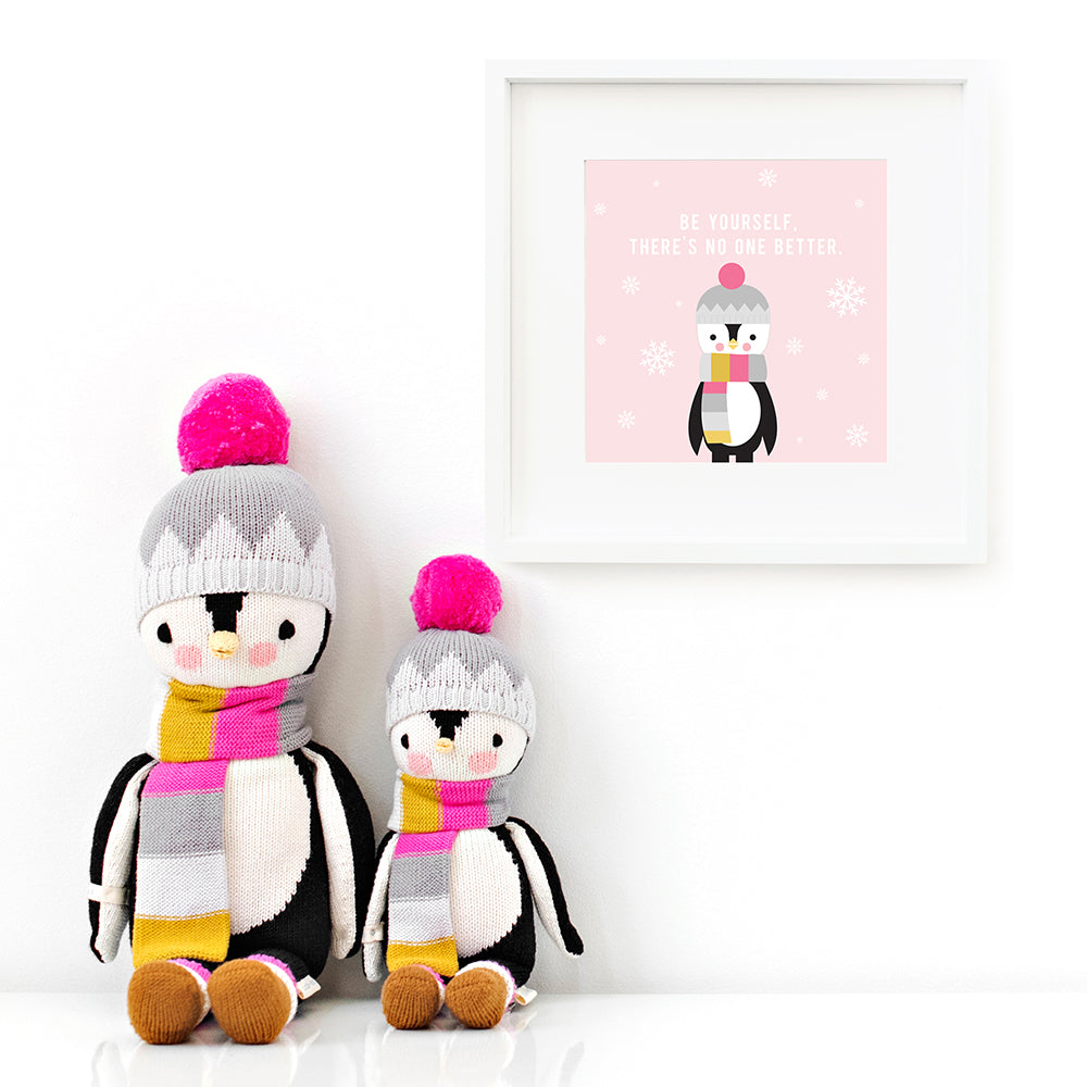Two Aspen the penguin stuffed animals sitting beside a framed print with a picture of Aspen that says “Be yourself. There’s no one better.”