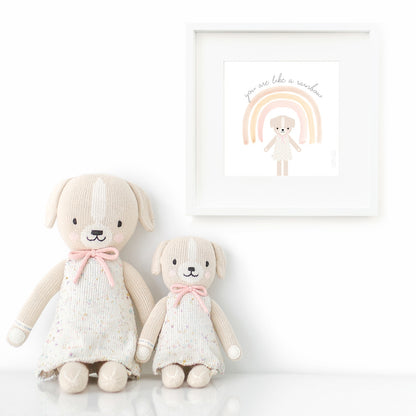 Two Mia the dog stuffed dolls sitting beside a framed print with a picture of Mia that says “You are like a rainbow.”