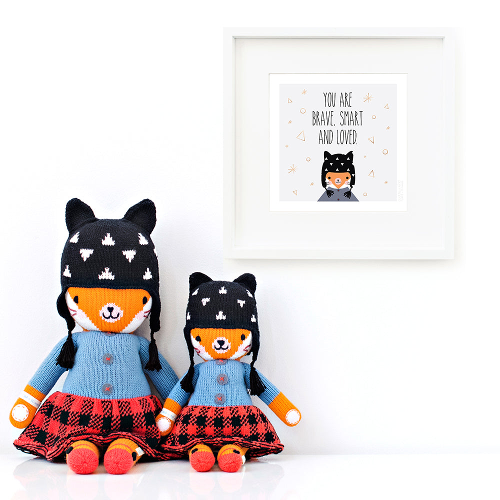Two Sadie the fox stuffed dolls sitting beside a framed print with a picture of Sadie that says “You are brave, smart and loved.”