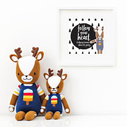 Two Scout the deer stuffed dolls sitting beside a framed print with a picture of Scout that says “Follow your heart. It always knows where it’s going.”