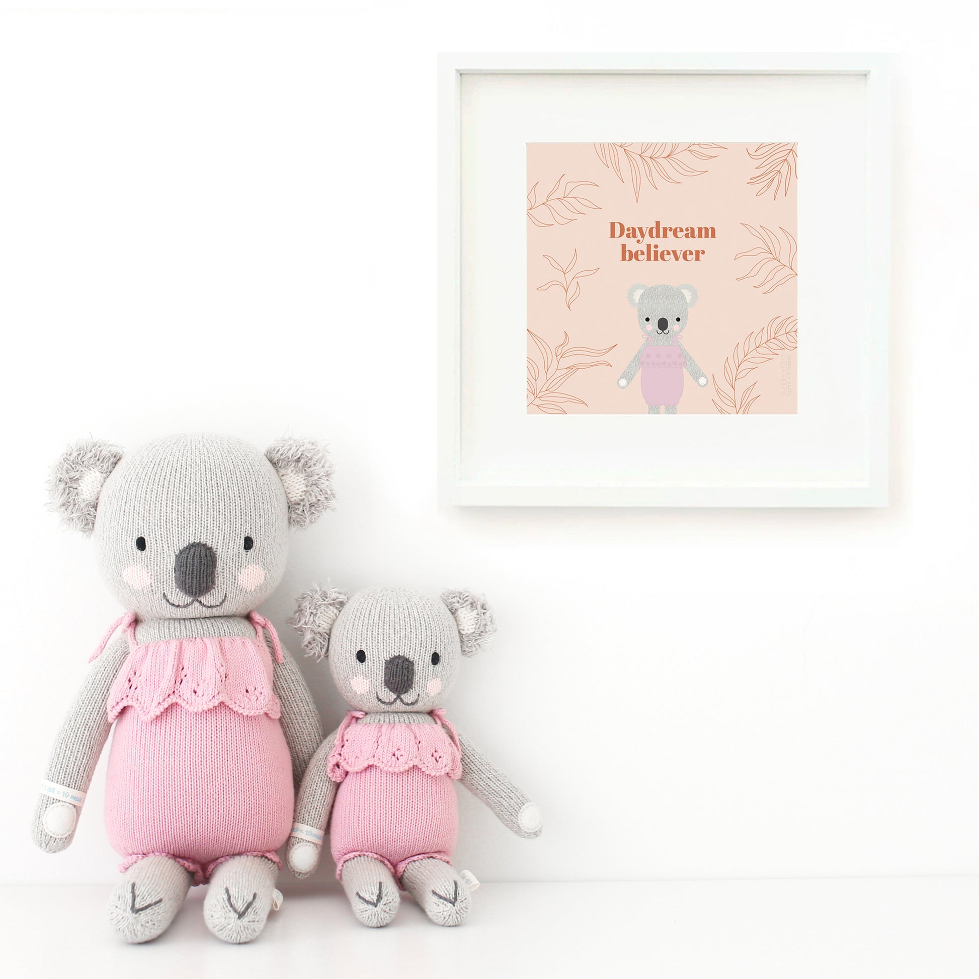 Two Claire the koala stuffed dolls sitting beside a framed print with a picture of Claire that says “Daydream believer.”