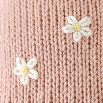 A close-up showing daisies embroidered onto Daisy the kitten’s romper.