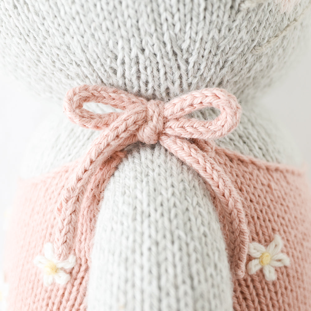 A close-up showing a hand-knit bow on Daisy the kitten’s romper.