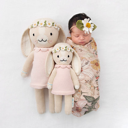A sleeping baby, wearing a daisy headband, with two Hannah the bunny dolls in the regular and little sizes.