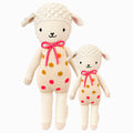 Lucy the lamb in the regular and little sizes, shown from the front. Lucy’s outfit has pink, gold and orange polka dots. She has a bright pink bow.