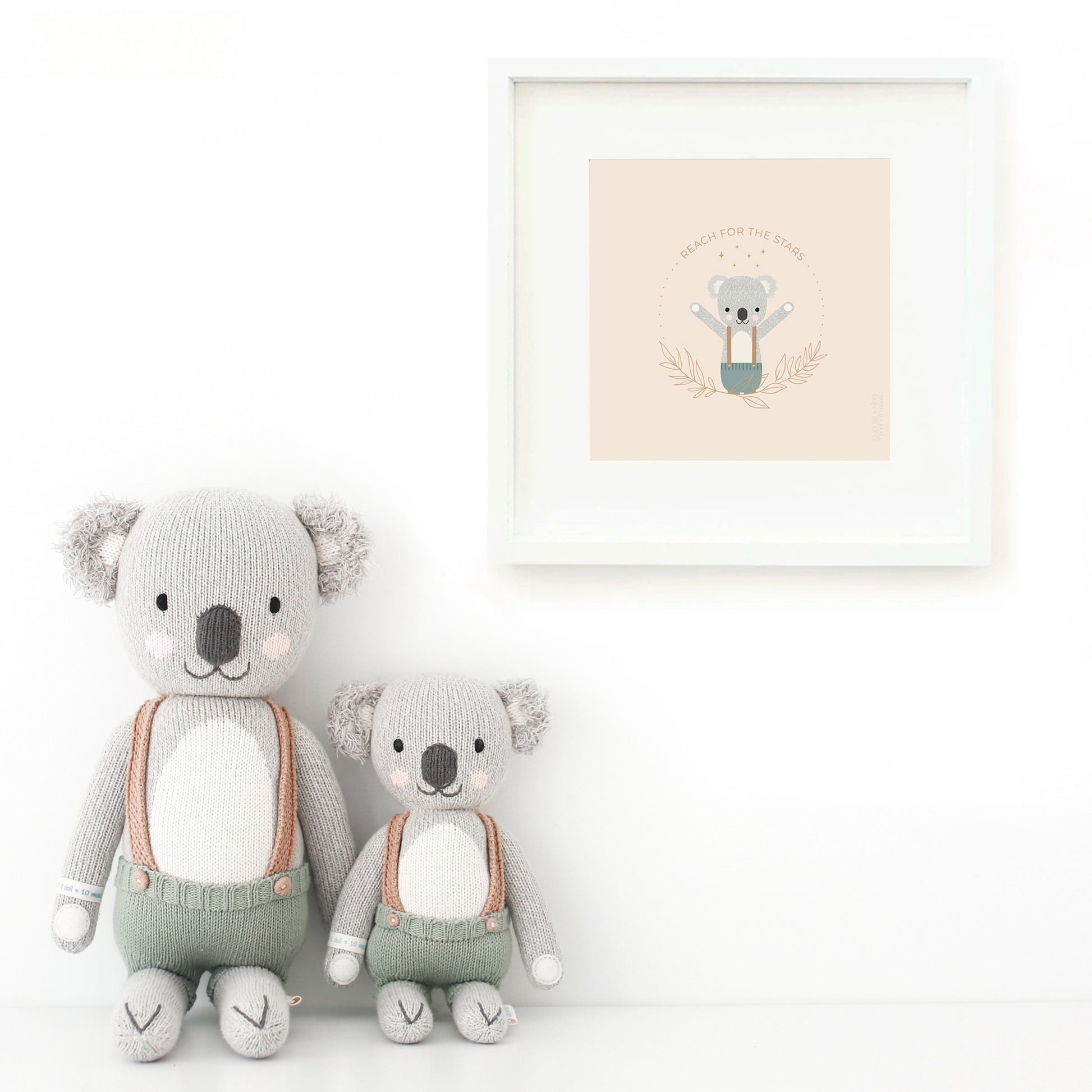 Two Quinn the koala stuffed dolls sitting beside a framed print with a picture of Quinn that says “Reach for the stars.”