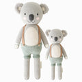 Quinn the koala in the regular and little sizes, shown from the front. Quinn is wearing green shorts with brown suspenders.