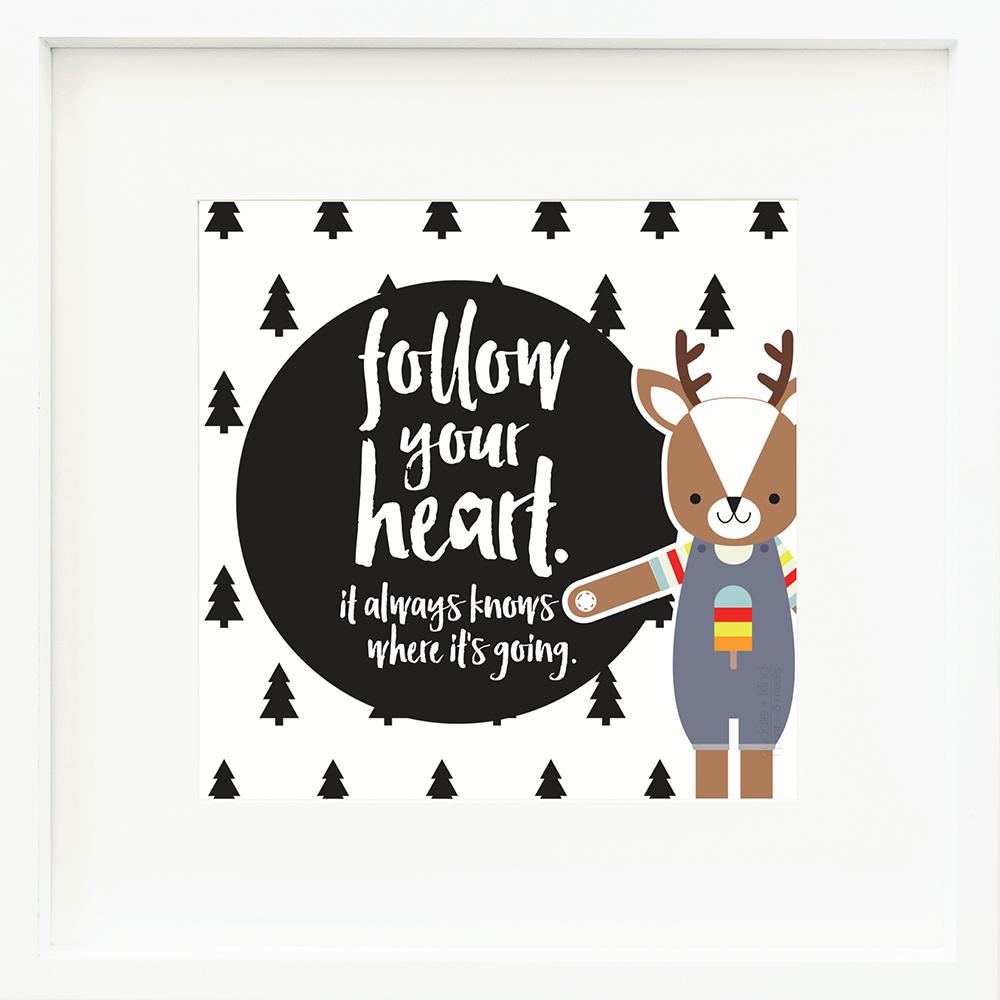 An inspirational print with a graphic of Scout the deer on a white background decorated with black icons of evergreen trees. The words “Follow your heart. It always knows where it’s going” are in white on a black circle.